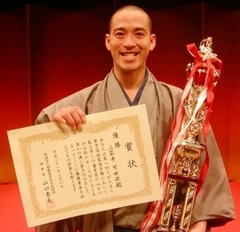 さがみはら若手落語家選手権の優勝トロフィーと賞状を手に、笑顔の三笑亭可女次さんの写真